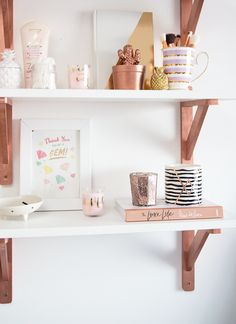 two white shelves with pink and gold decor on them, one shelf is filled with personal items