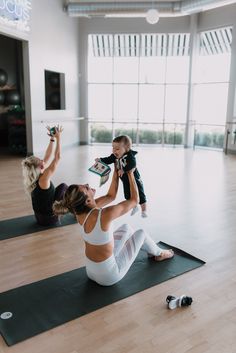 a woman and child are doing yoga in the middle of a room with large windows