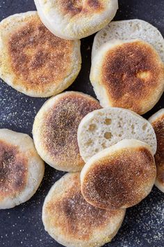 several pieces of bread sitting on top of a black plate next to some seasoning