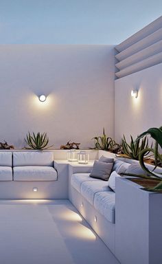 a living room filled with lots of white furniture and plants on top of the couches