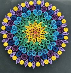 a colorful circular design made out of rolled up paper on top of a black surface