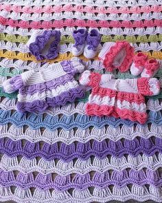 crocheted baby clothes and shoes are laid out on a blanket that is laying on the floor