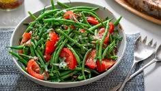 a white bowl filled with green beans and tomatoes