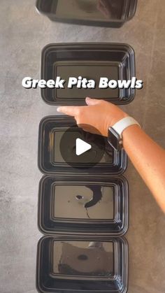 a person pointing at three black trays with food in them and the words greek pita bowls