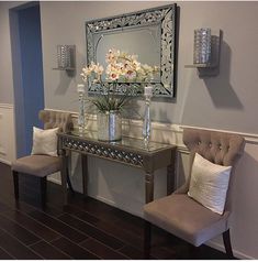 two chairs sitting next to a table with flowers in vases on top of it