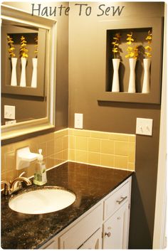 there is a sink in the bathroom with yellow flowers on the wall above it and two mirrors