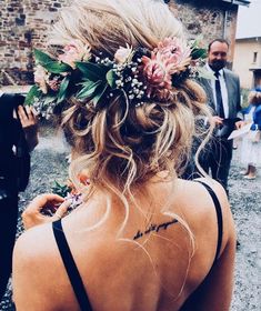 the back of a woman's head with flowers in her hair and other people standing around