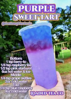 the purple sweet tart is being held up in front of a park with trees