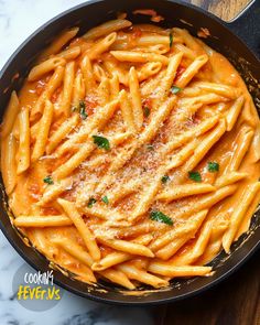 pasta with sauce and parmesan cheese in a skillet on a marble table