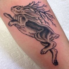 a black and white tattoo of a rabbit on the back of a person's leg