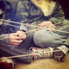 two people sitting on the floor playing with string