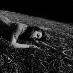 a black and white photo of a woman laying in the grass