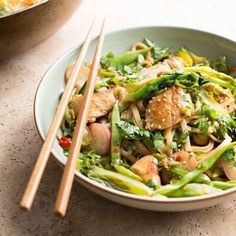 a bowl filled with noodles and vegetables next to chopsticks