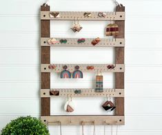 a wall mounted wooden ruler holder with earrings and other items hanging on it's sides