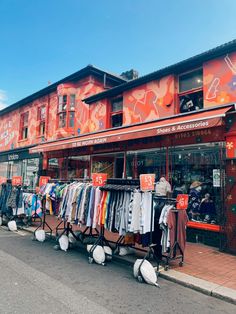 an outdoor clothing store with lots of clothes on display in front of the storefront