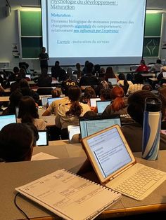 a classroom full of students with laptops and projectors in front of the class room