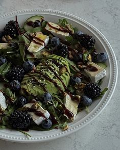 a white plate topped with a salad covered in fruit