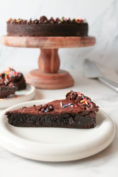 a slice of chocolate cake with sprinkles on a plate next to another piece