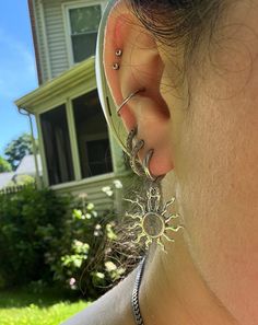 a woman with ear piercings on her ears in front of a house