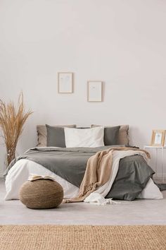 a bedroom with white walls and grey bedding, rugs and pictures on the wall