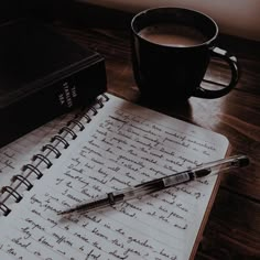 an open notebook with writing on it next to a cup of coffee and a pen