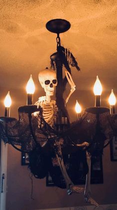 a chandelier decorated with candles and a skeleton hanging from it's side