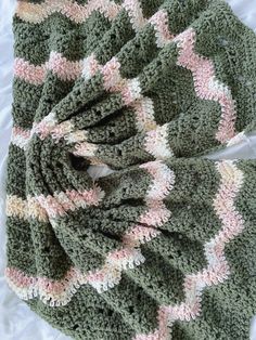 a crocheted blanket laying on top of a bed next to a pair of scissors