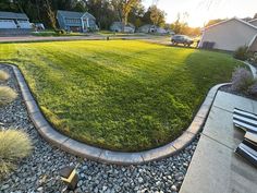 an empty lawn in the middle of a residential area with gravel edging around it