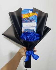 a hand holding a bouquet of blue roses with a hot wheels card in the back