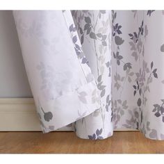 a close up view of a curtain with flowers on the fabric and wood flooring