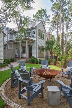 a fire pit surrounded by chairs in front of a house