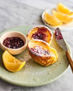 lemons and powdered sugar sit on a plate next to some bread with jam