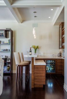 a kitchen with two bar stools next to a counter top and wine bottles on the shelves