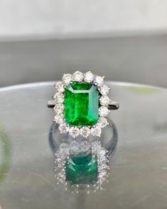 Formal Emerald Ring With Halo Setting, Elegant Green Gemstone Halo Ring, Elegant Green Emerald Ring With Halo Setting, Elegant Green Diamond Ring With Halo Design, Dazzling Green Diamond Ring, Classic Green Cluster Diamond Ring, Luxury Emerald Cluster Ring With Halo Setting, Luxury Cluster Emerald Ring, Luxury Cluster Emerald Ring With Halo Setting