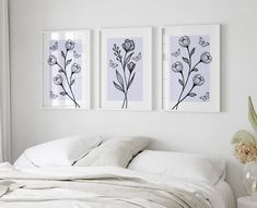 three framed pictures hang on the wall above a bed with white linens and pillows