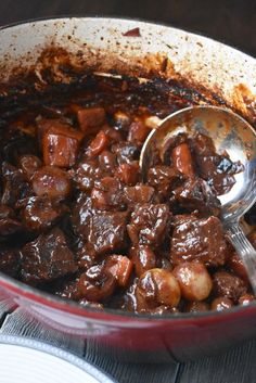 a pot filled with meat and potatoes on top of a wooden table