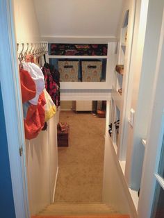 an open door leading to a closet with clothes hanging on the rack and other items