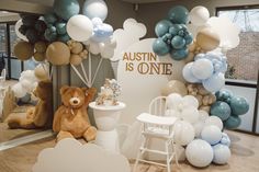 there is a teddy bear sitting in front of balloons and other decorations on the wall