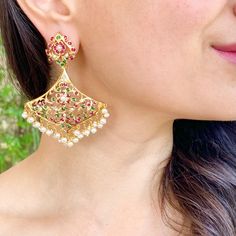 Featuring a pair of edwardian era inspired, jadau earrings in gold plated silver. It has been embellished with freshwater pearls and synthetic red and greed stones that closely resemble rubies and emeralds. The earrings weigh about 25grams and have a smooth roll-on-roll-off bombay screw closure. All of Rudradhan's Gold Plated Jewellery is made using 925 Silver, real freshwater pearls and high quality ruby, emerald and sapphire beads. The default choice for studded stones used is synthetic that c Elegant Jeweled Chandbali Pearl Earrings, Elegant Jeweled Pearl Earrings For Festive Occasions, Ornate Jeweled Earrings For Festive Occasions, Kundan Bridal Earrings In Temple Jewelry Style, Kundan Temple Jewelry Bridal Earrings, Kundan Bridal Earrings With Elegant Temple Design, Elegant Gold-plated Meenakari Pearl Earrings, Elegant Meenakari Gold-plated Pearl Earrings, Chandbali Jeweled Temple Jewelry Bridal Earrings