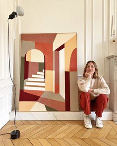 a woman sitting on the floor in front of a painting