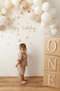 a toddler standing in front of a birthday backdrop