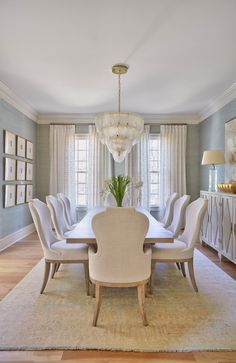 a dining room table with white chairs and a chandelier