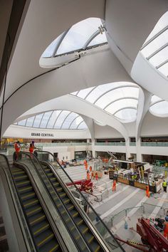 an escalator and some people in orange safety vests are standing near the escalators