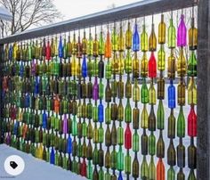 a fence made out of wine bottles is shown in front of the snow covered ground