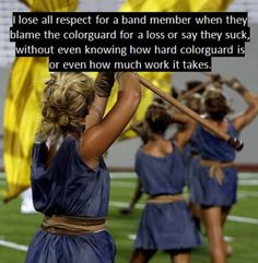 a group of women in blue dresses holding onto yellow umbrellas on a football field