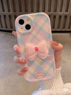 a person holding up a cell phone case with a bow on the front and side