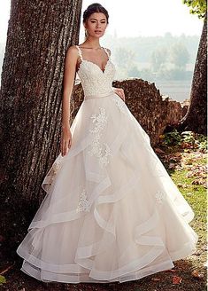 a woman standing next to a tree wearing a wedding dress