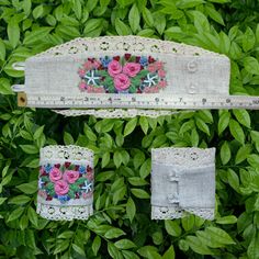 two pieces of fabric with flowers on them are hanging from a ruler in the bushes