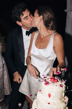 a bride and groom are kissing while cutting their wedding cake at the end of the night