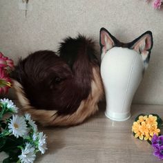 a dog laying next to a vase with flowers